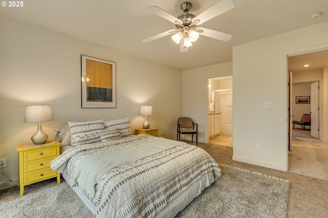 carpeted bedroom featuring ensuite bath, a ceiling fan, and baseboards