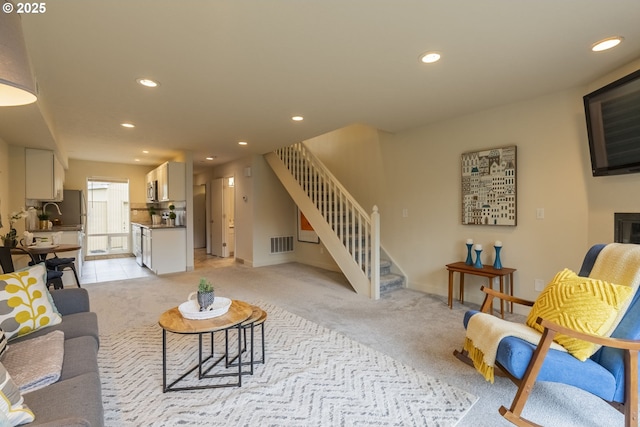 living room featuring light carpet, visible vents, recessed lighting, and stairs