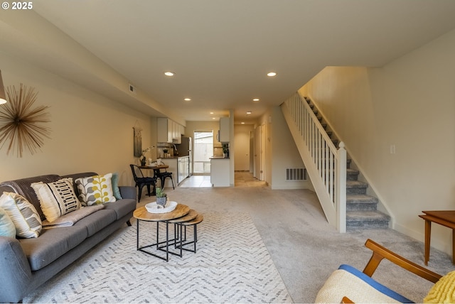 living room featuring visible vents, baseboards, recessed lighting, stairs, and light colored carpet