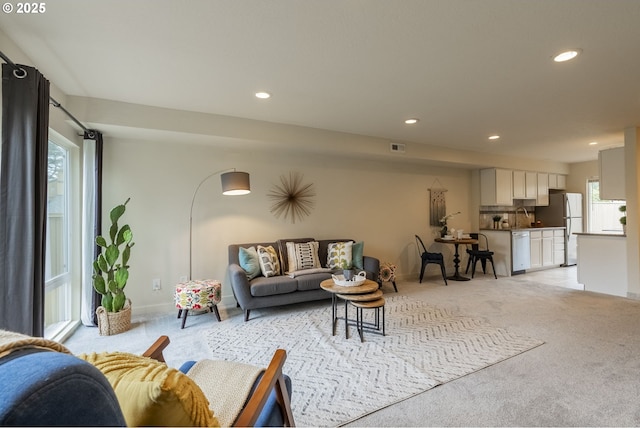 living room with light carpet, visible vents, recessed lighting, and baseboards