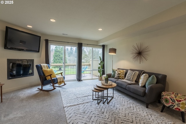 carpeted living area with recessed lighting, visible vents, baseboards, and a glass covered fireplace