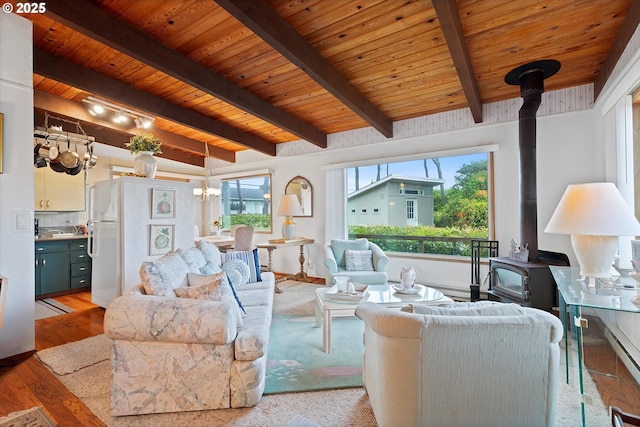 320 El Rotundo Ave, Lincoln City, OR 97367 - living area with a wood stove, wooden ceiling with exposed beams, light wood-style flooring, and a chandelier