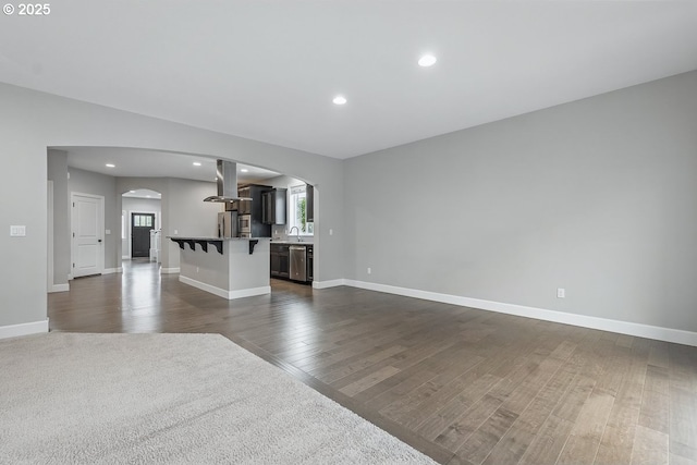 7698 NW Catalpa St, Portland, OR 97229 - unfurnished living room featuring arched walkways, dark wood-style flooring, baseboards, and recessed lighting
