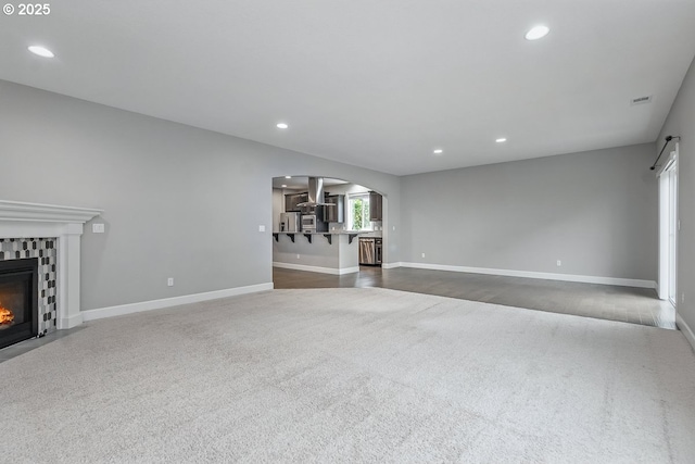 7698 NW Catalpa St, Portland, OR 97229 - unfurnished living room featuring arched walkways, dark colored carpet, a fireplace, recessed lighting, and baseboards