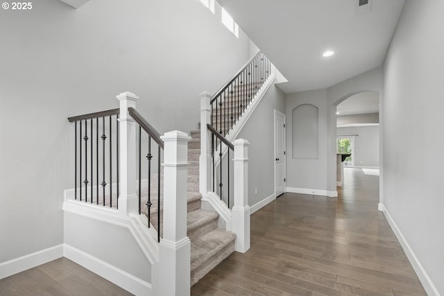 7698 NW Catalpa St, Portland, OR 97229 - staircase featuring arched walkways, wood finished floors, baseboards, and recessed lighting