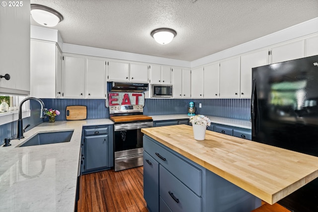 3131 Alyndale Dr, Eugene, OR 97404 - kitchen featuring stainless steel appliances, a sink, under cabinet range hood, butcher block countertops, and blue cabinets