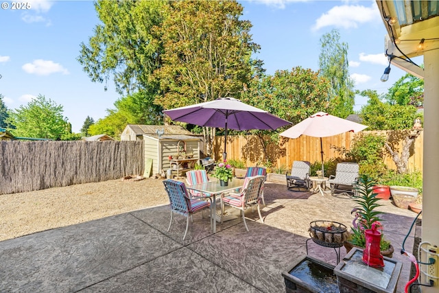 view of patio / terrace featuring a storage shed, outdoor dining area, a fenced backyard, and an outdoor structure