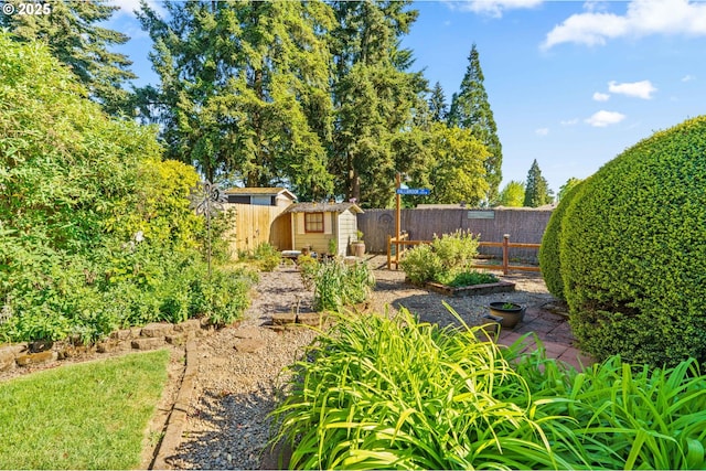 fenced backyard with a shed, an outdoor structure, and a garden
