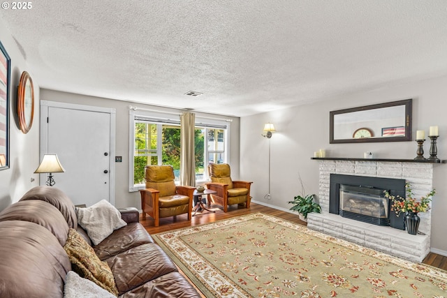 living area featuring wood finished floors, a textured ceiling, a fireplace, and baseboards