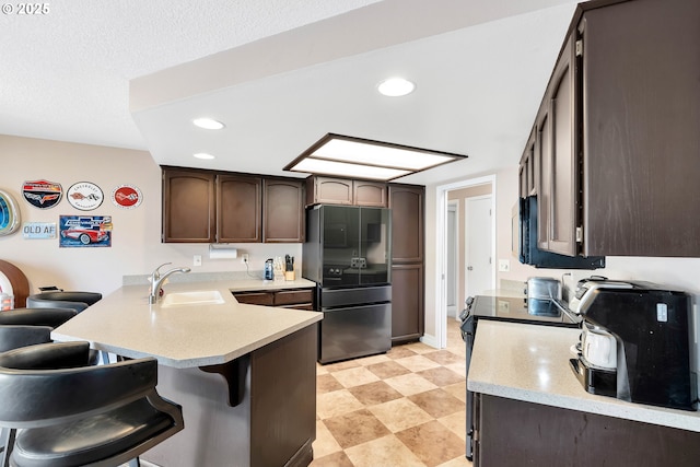 10903 NW 5th Ave, Vancouver, WA 98685 - kitchen with freestanding refrigerator, a peninsula, a sink, a breakfast bar area, and dark brown cabinets