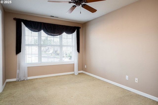 carpeted empty room featuring a ceiling fan, visible vents, and baseboards