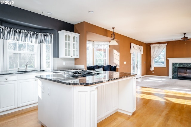 kitchen featuring open floor plan, a fireplace, glass insert cabinets, and a healthy amount of sunlight