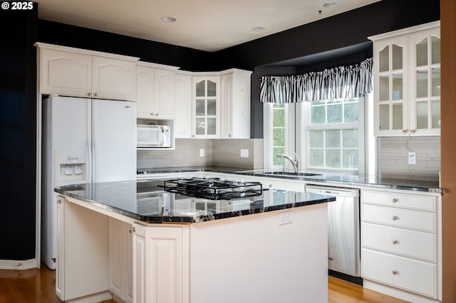 kitchen featuring white appliances, glass insert cabinets, white cabinets, and a center island