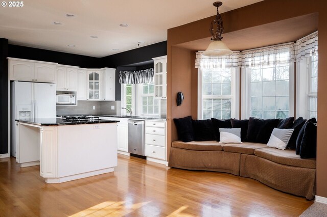 kitchen with glass insert cabinets, white appliances, white cabinets, and open floor plan