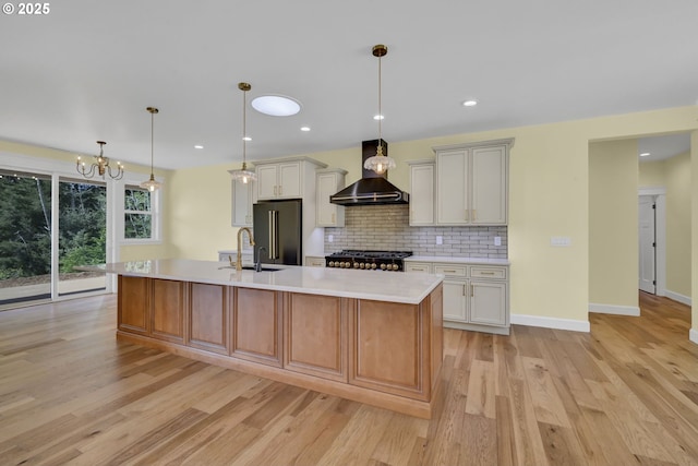 83594 Sauter Dr, Florence, OR 97439 - kitchen with high end black fridge, wall chimney exhaust hood, light countertops, a sink, and light wood-type flooring