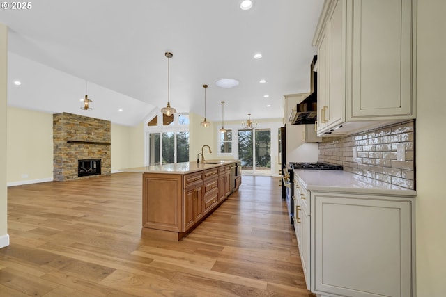 83594 Sauter Dr, Florence, OR 97439 - kitchen with high end stainless steel range oven, light countertops, light wood-style floors, a fireplace, and a center island with sink