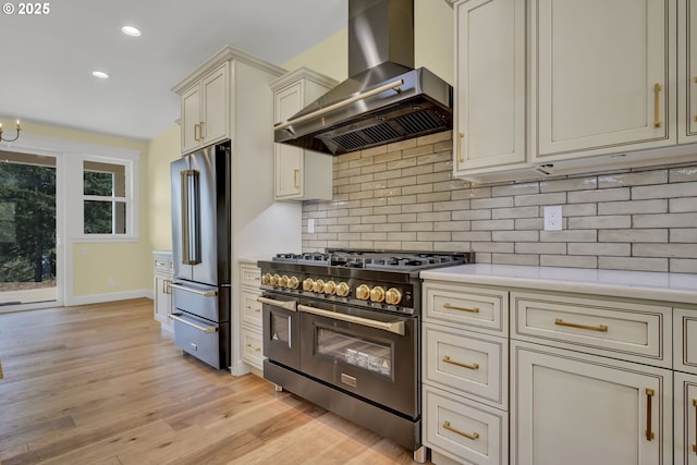 83594 Sauter Dr, Florence, OR 97439 - kitchen featuring wall chimney exhaust hood, premium appliances, cream cabinets, light countertops, and light wood-style floors