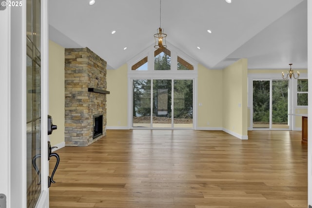 83594 Sauter Dr, Florence, OR 97439 - unfurnished living room with a chandelier, healthy amount of natural light, a stone fireplace, baseboards, and high vaulted ceiling