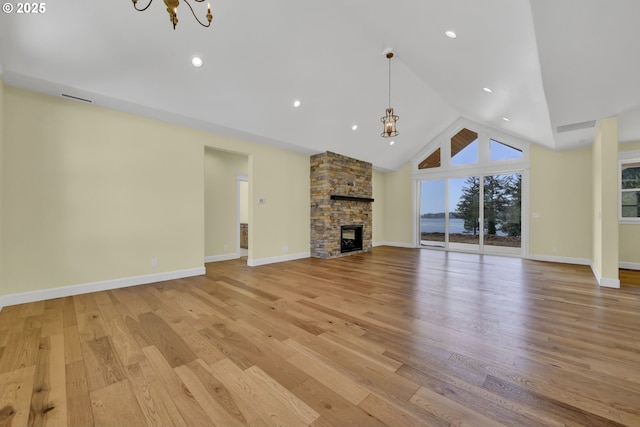 83594 Sauter Dr, Florence, OR 97439 - unfurnished living room featuring a chandelier, light wood-style flooring, a fireplace, vaulted ceiling, and baseboards
