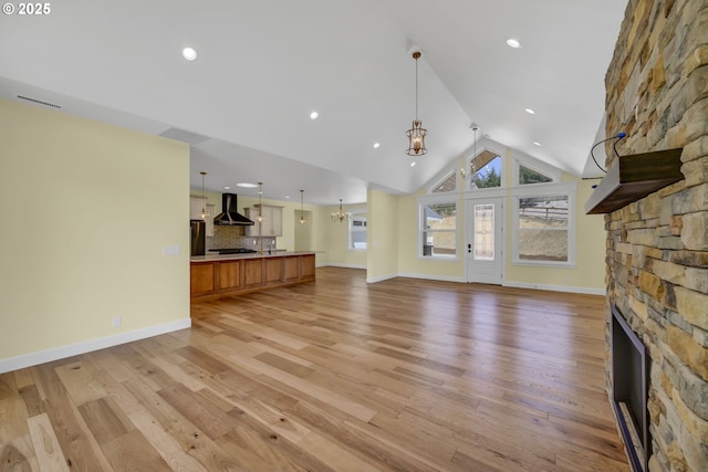83594 Sauter Dr, Florence, OR 97439 - unfurnished living room featuring a fireplace, vaulted ceiling, a chandelier, light wood-type flooring, and baseboards