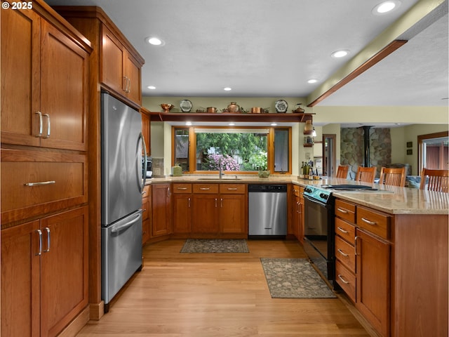24880 E Arrah Wanna Blvd, Welches, OR 97067 - kitchen with stainless steel appliances, a sink, light wood-style flooring, brown cabinets, and recessed lighting