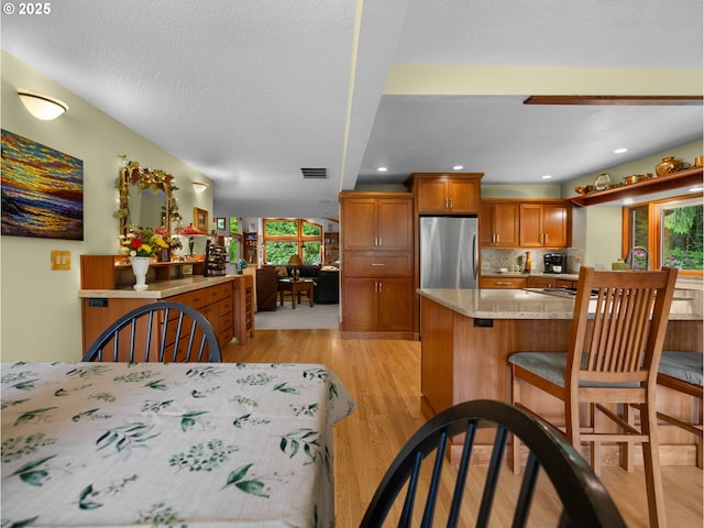 24880 E Arrah Wanna Blvd, Welches, OR 97067 - kitchen with stainless steel refrigerator, healthy amount of natural light, brown cabinets, light wood-style floors, and recessed lighting