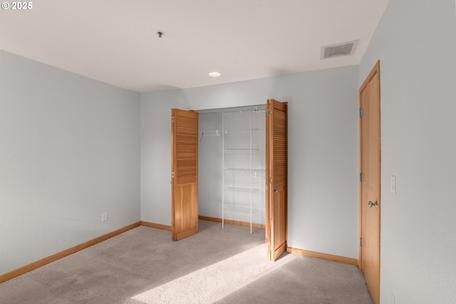 unfurnished bedroom with light colored carpet and a closet