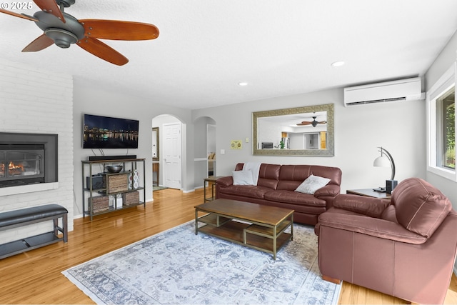 819 SE 98th Ave, Vancouver, WA 98664 - living room featuring a wall unit AC, ceiling fan, arched walkways, wood finished floors, and a fireplace