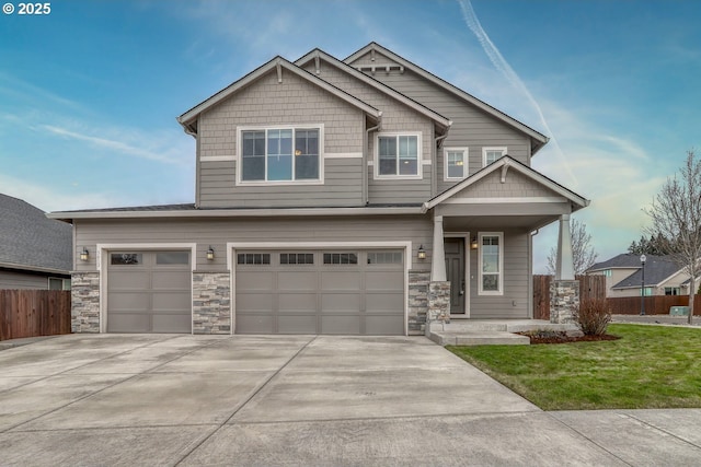 craftsman-style house featuring an attached garage, fence, driveway, stone siding, and a front lawn