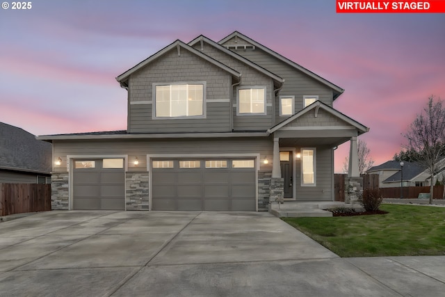 craftsman house featuring fence, concrete driveway, a lawn, stone siding, and an attached garage