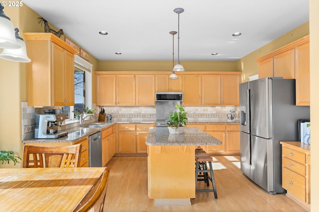 kitchen featuring a breakfast bar area, decorative light fixtures, a center island, light brown cabinets, and stainless steel appliances