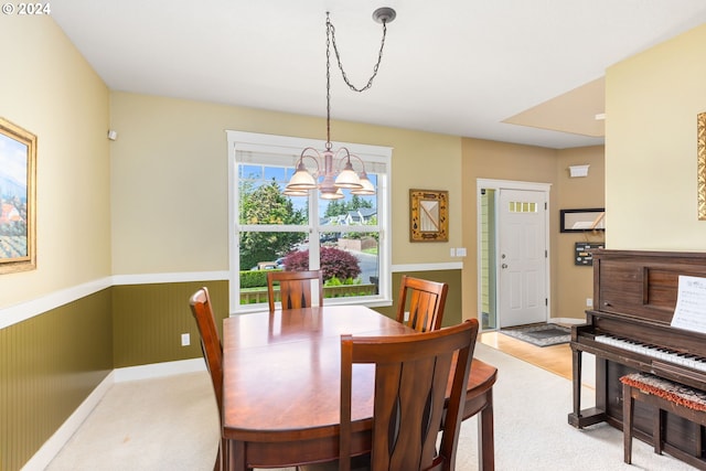 carpeted dining room with a notable chandelier and wooden walls