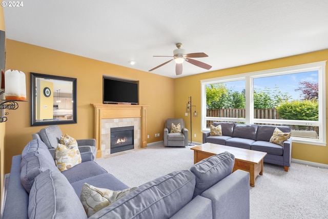 carpeted living room with a tile fireplace and ceiling fan