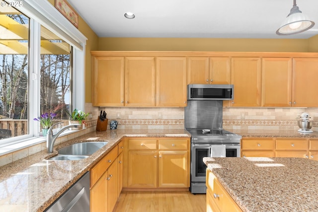 kitchen with appliances with stainless steel finishes, sink, pendant lighting, and decorative backsplash