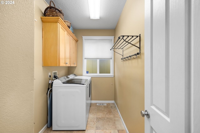 clothes washing area with cabinets, washer and dryer, and a textured ceiling