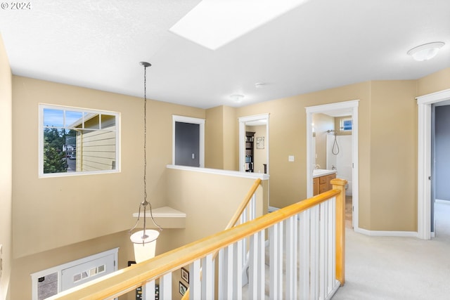 hallway with light carpet and a skylight