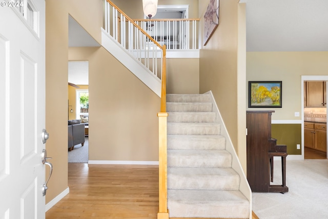 staircase with hardwood / wood-style flooring and a towering ceiling