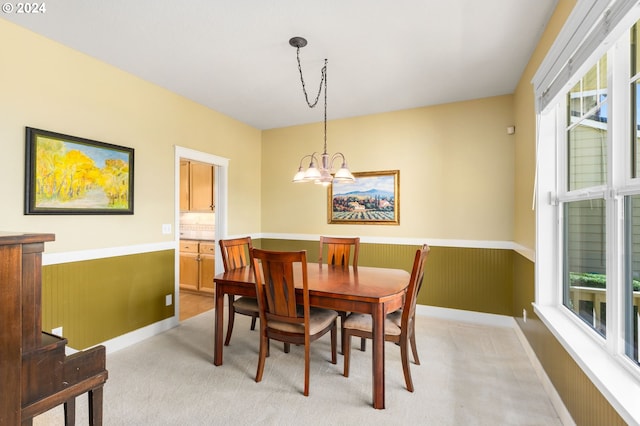 carpeted dining space featuring a chandelier