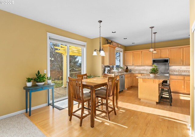 kitchen featuring a kitchen island, appliances with stainless steel finishes, light stone counters, and light brown cabinetry