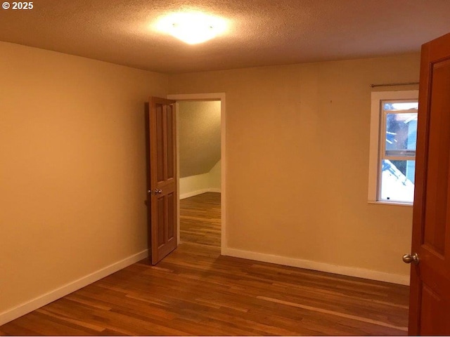 empty room with dark hardwood / wood-style flooring and a textured ceiling