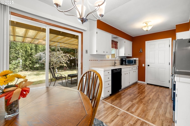 15870 SW Royalty Pkwy, King City, OR 97224 - kitchen featuring dishwasher, stainless steel microwave, white cabinetry, a chandelier, and fridge
