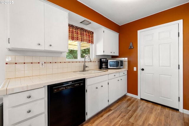 15870 SW Royalty Pkwy, King City, OR 97224 - kitchen featuring black dishwasher, stainless steel microwave, tile counters, white cabinetry, and decorative backsplash