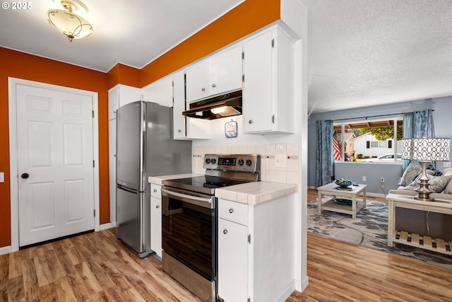 15870 SW Royalty Pkwy, King City, OR 97224 - kitchen featuring stainless steel appliances, under cabinet range hood, tile counters, light wood finished floors, and a textured ceiling