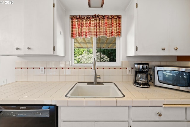 15870 SW Royalty Pkwy, King City, OR 97224 - kitchen with black dishwasher, stainless steel microwave, white cabinetry, and decorative backsplash