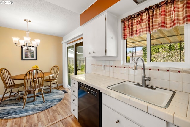 15870 SW Royalty Pkwy, King City, OR 97224 - kitchen with black dishwasher, tile countertops, white cabinetry, a chandelier, and a textured ceiling