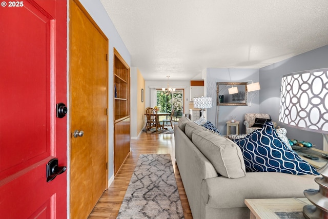 15870 SW Royalty Pkwy, King City, OR 97224 - living area featuring light wood-style flooring, a textured ceiling, and a chandelier
