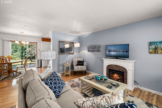 15870 SW Royalty Pkwy, King City, OR 97224 - living room with a textured ceiling, a chandelier, light wood-style flooring, and a lit fireplace