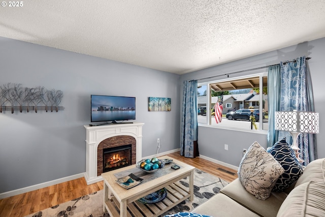 15870 SW Royalty Pkwy, King City, OR 97224 - living room featuring a textured ceiling, wood finished floors, and a lit fireplace