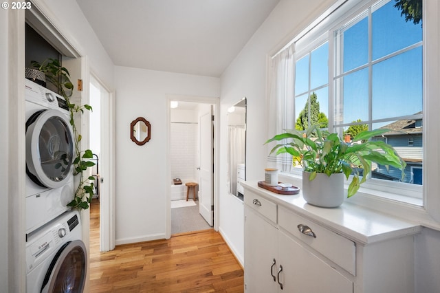 laundry room with stacked washer and clothes dryer and light hardwood / wood-style floors