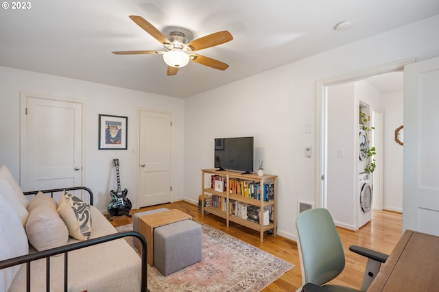 living room with ceiling fan, stacked washer / drying machine, and light hardwood / wood-style floors